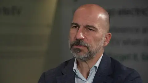 達拉·科斯羅薩西 (Dara Khosrowshahi) 的頭部和肩部照片，開領襯衫