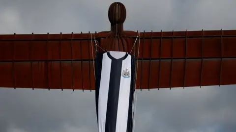 The Angel of the North with a black and white Newcastle United shirt hanging from the statue's body.