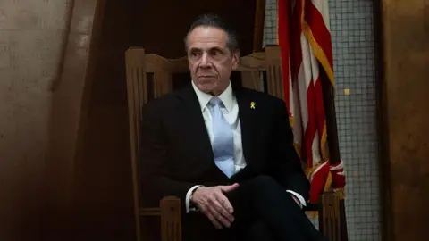 Man sits with hand on his knee in wooden rocking chair