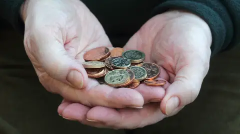 Getty Images Man holding British coins