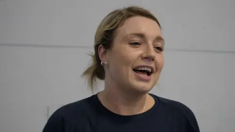 Jamie Niblock/BBC Sophie has short blonde hair, tied back in a short bun. She is slightly sweaty, having been interviewed mid match