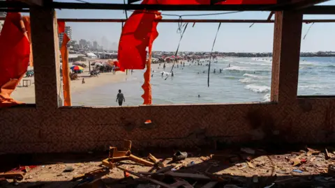 A general view of a site following an Israeli airstrike on Al-Baqa cafeteria. Gaping windows and ripped, red awning can be seen in the foreground. 