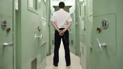 PA Media Prison officer stands in prison