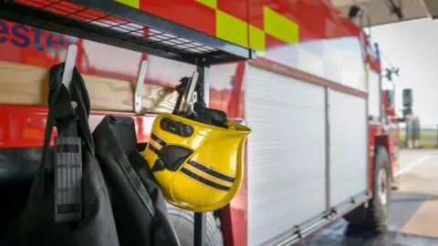 A stock image of firefighter's yellow helmet hanging from a fire engine