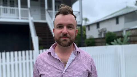 Sam stands in front of his house and looks into the camera