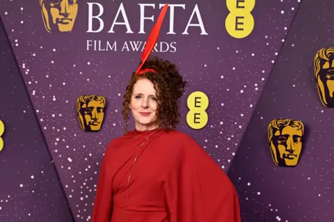 Getty Images Maggie O'Farrell in a red dress with a red quill headpiece