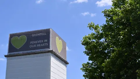 GLYN KIRK/GETTY Grenfell Tower with the words Forever in our hearts.