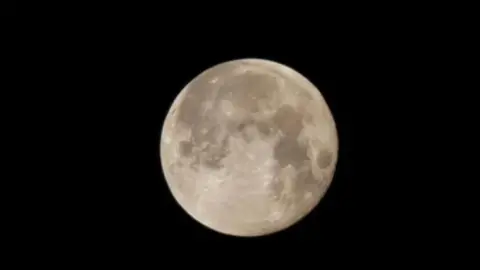 BBC Weather Watchers/tammynew The large full moon shines in white in the dark sky. 