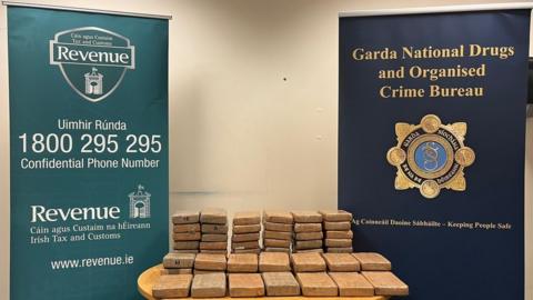 Blocks of cocaine are stacked up next to posters for An Garda Siochana and Revenue