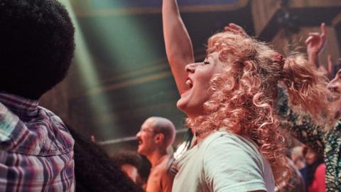 A woman cheering in a crowd at a gig