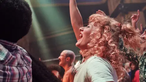 Getty Images A woman cheering in a crowd at a gig