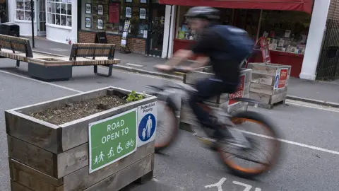 Getty Images A blurred cyclist passes through the barriers that form an LTN (Low Traffic Neighbourhood), an experimental closure by Southwark Council preventing motorists from accessing the junction of Carlton Avenue and Dulwich Village