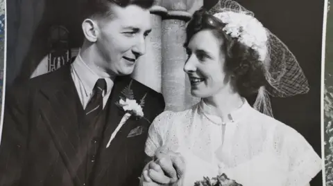 Rita Harvey / Royal Star & Garter a black and white photo of a couple clasping hands and gazing lovingly at each other after getting married