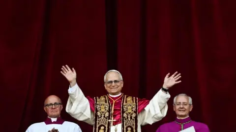 Pope Leo waves to crowds from the balcony in St Peter's Square.
