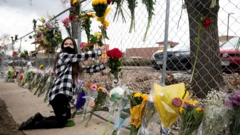 Reuters A teenage girl leaves flowers at the site of a mass shooting at King Soopers grocery store in Boulder, Colorado, U.S. March 23, 2021.