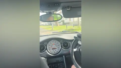 Avon and Somerset Police A screenshot taken from the video footage taken from the inside of the Black Mini that was being driven by the teenagers. The image has been taken by a rear-seat passenger and shows the wheel and the dashboard of the car and a sunny street in the windscreen.
