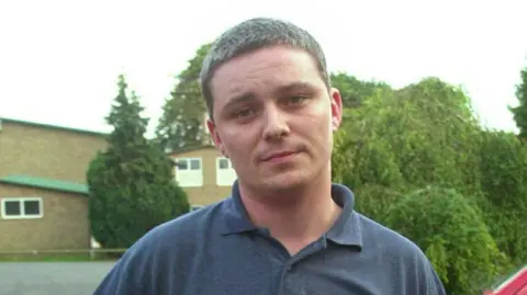 PA Media Ian Huntley standing in front of a row of houses and trees 