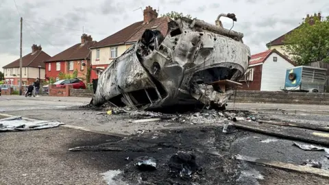 A torched car upside down on a road