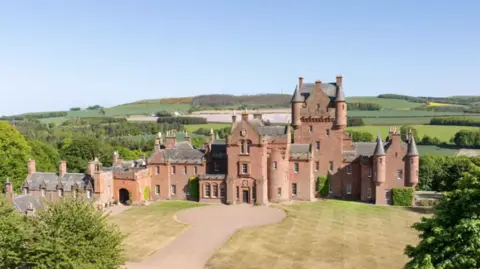 Knight Frank A long distance view of Ayton Castle a grand building surrounded by hills and trees