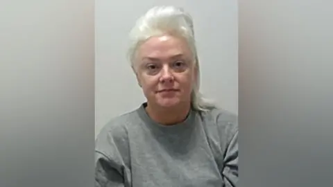 Lancashire Police Catherine Hudson has no expression on her face in her mugshot. She is wearing a grey jumper and has her hair tied back.