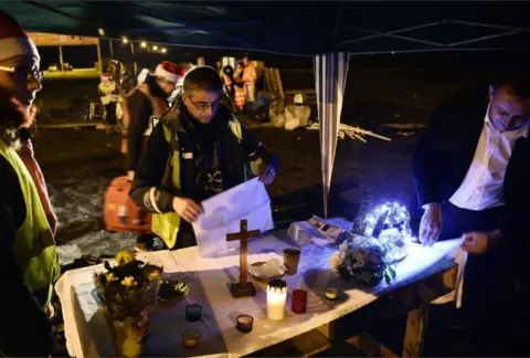 AFP/Getty Images A priest prepares for a Christmas Eve mass for "yellow vests" protesters near a roundabout in Somain, northern France