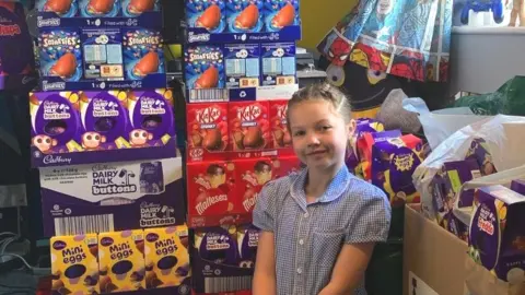 Charlene Spackman Ellie in her school uniform surrounded by stacks of Easter eggs in their boxes