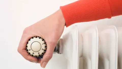 Getty Images Someone adjusting a thermostat on a radiator