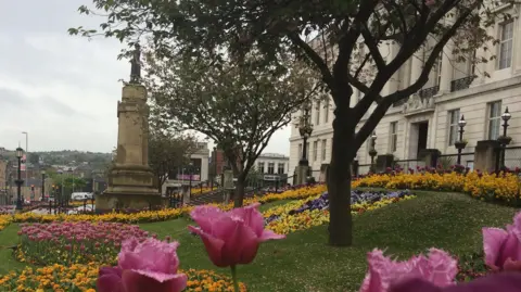 Barnsley town hall, flowers in the foreground and a war memorial in the distance