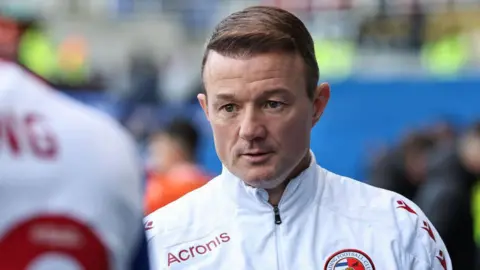 Getty Images Noel Hunt wearing a white Reading jacket looking into the distance at a Reading match.