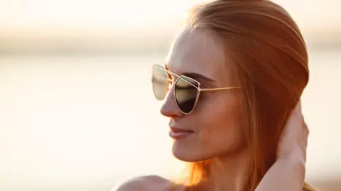 Getty Images A woman with long hair is wearing sunglasses with thin arms