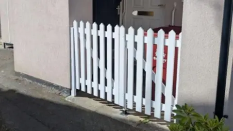 White gates on the entrance of a pebbledash home