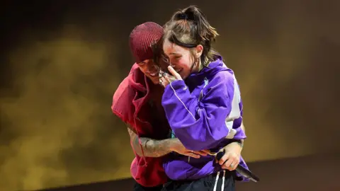Kevin Mazur/Getty Images Justin Bieber hugs Billie Eilish, who is cry-laughing, on stage