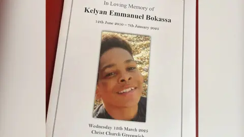 Kelyan's Funeral Order Of Service, with a picture of him smiling in the centre surrounded by the words 'In Loving Memory of Kelyan Emmanuel Bokassa. 12th June 2010 - 7th January 2025'. Underneath the picture reads 'Wednesday 12th March 2025. Christ Church Greenwich'.