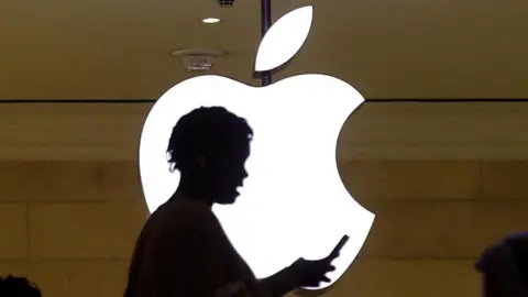 Reuters A person on their phone in front of the Apple logo