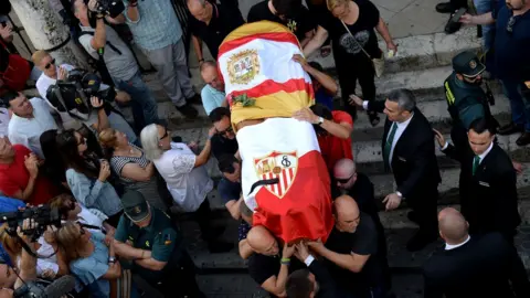 The coffin with the remains of Spanish footballer Jose Antonio Reyes, covered with the flags of the village of Utrera and Sevilla FC football team, is carried on shoulders to the Santa Maria de Mesa church in Utrera during his funeral, 3 June 2019