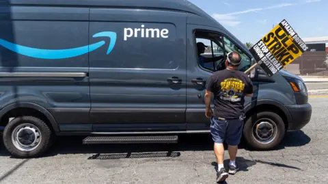 Teamsters union members talks to a truck driver at an Amazon facility in Los Angeles during a labour a strike in 4 August, 2024.