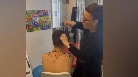 Supplied A photo taken from behind of a young boy sitting in a white chair while a woman cuts his hair.