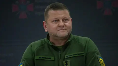 Getty Images Valerii Zaluzhnyi speaks at a conference. He is wearing military fatigues and has a microphone. 