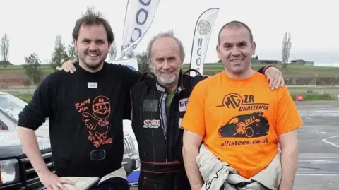 Sharpe family The family stood at a racing circuit smiling for a photo