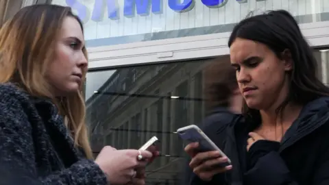 Getty Images Two women using mobile phones