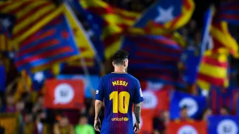 Player Lionel Messi of Barcelona football club looks on as Catalan pro-independence flags are seen in the background