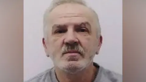Police mugshot of Eugeniu Neamtu, a man with short grey hair, a beard, and a moustache facing forward
