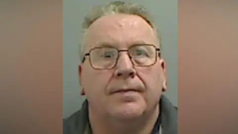 Mugshot of Coupland. He is clean shaven with glasses and short thin fair hair.