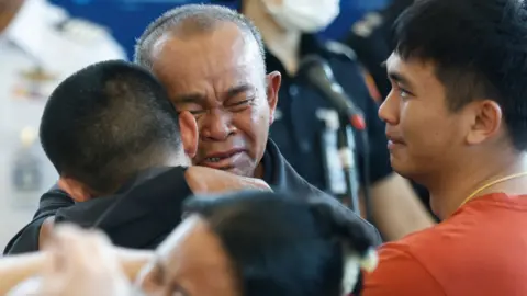 Reuters Thai Mortgage Pongsak Thanna (L), who was taken into an attack on 07 October 2023 led by Palestinian terrorist group Hamas, is hugged by his father (C) next to his younger brother