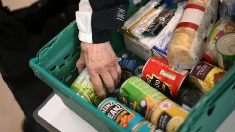 DANIEL LEAL/Getty Images A food bank parcel containing tins of food and non-perishable food items