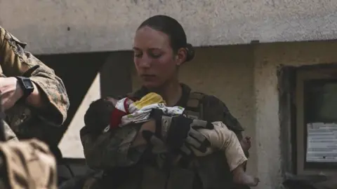 US DEPARTMENT OF DEFENSE US Marine Sgt Nicole Gee, holding an Afghan baby