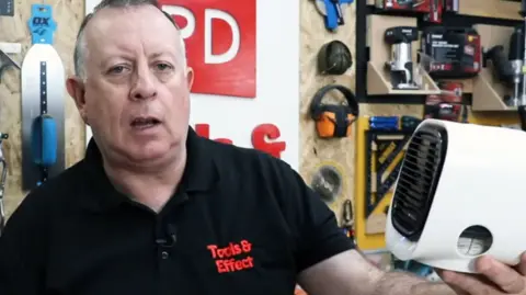 Proper DIY Stuart Matthews in a grab from his You Tube channel Proper DIY in a black t shirt holding the white cube fan
