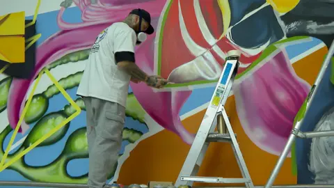 Woodie is using a spray paint on the mural wall.