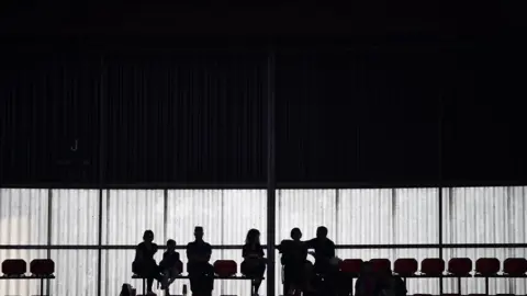 AFP The silhouettes of a group of people are seen in a football stadium.