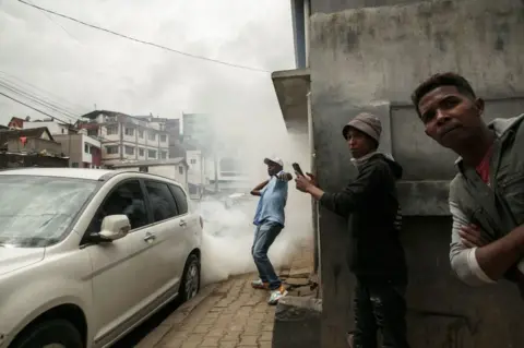 RIJASOLO/AFP A demonstrator prepares to throw a rock as they clash with police on their way to an opposition rally.